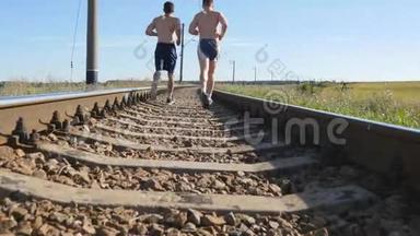 两个人在铁轨上的铁轨之间奔跑。 在铁路轨枕上慢跑的跑步者。 运动腿